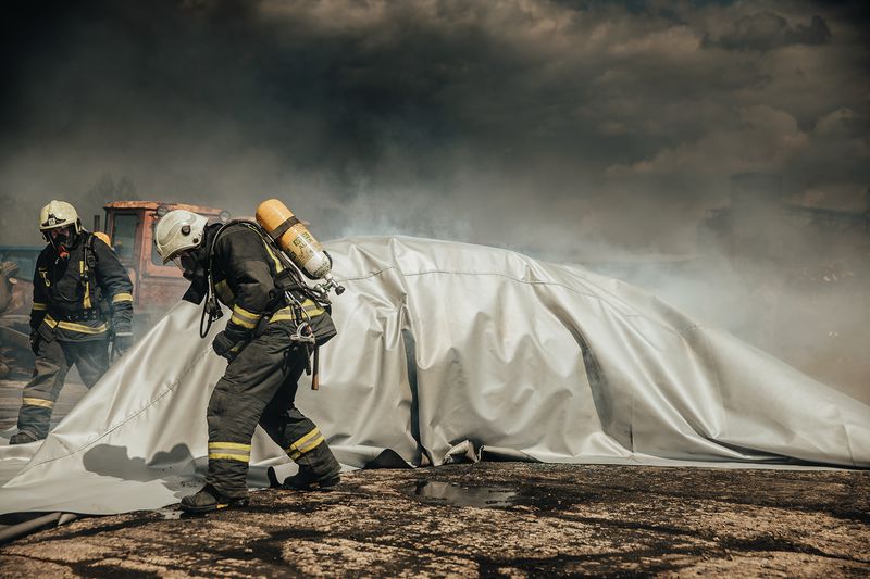 Voiture électrique recouverte d'une couverture anti-feu lithium pendant une intervention